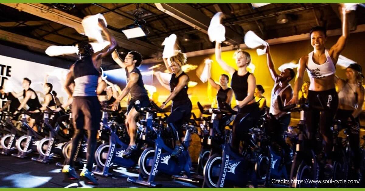 Lezione di indoor cycling immersiva con luci soffuse e workout total body
